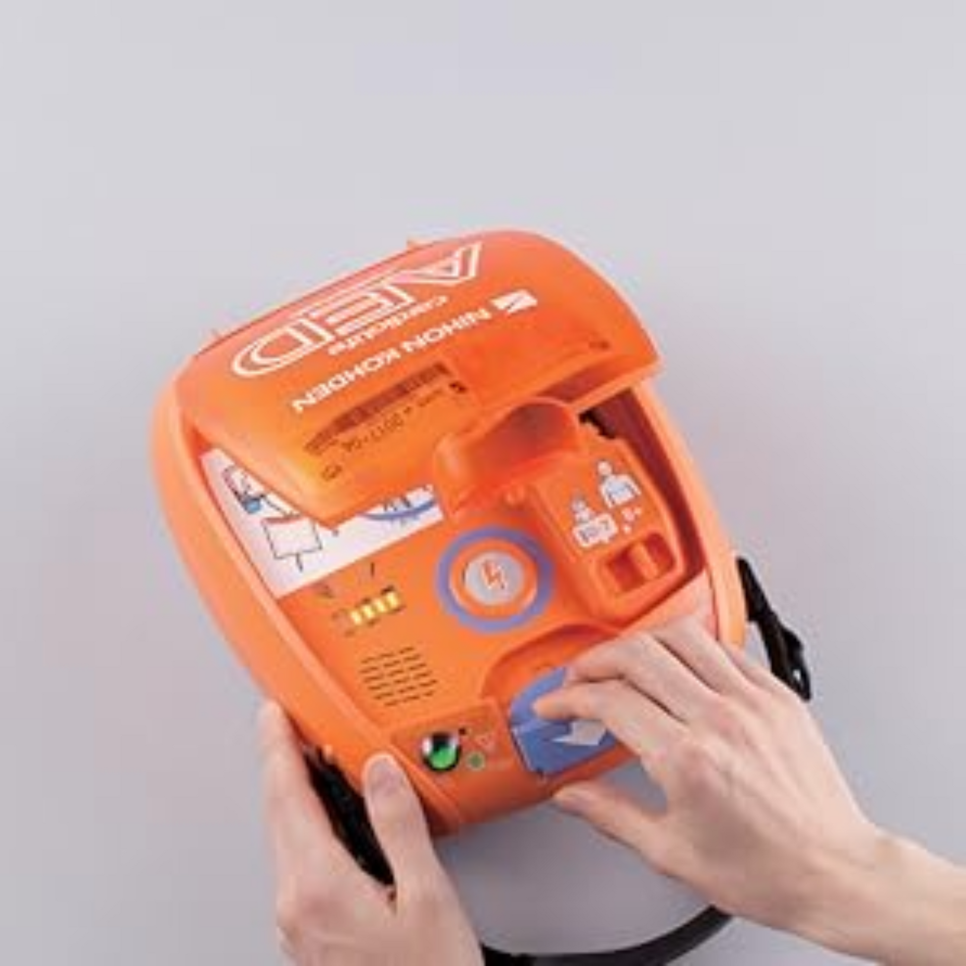 Orange AED device with hands interacting on a gray background