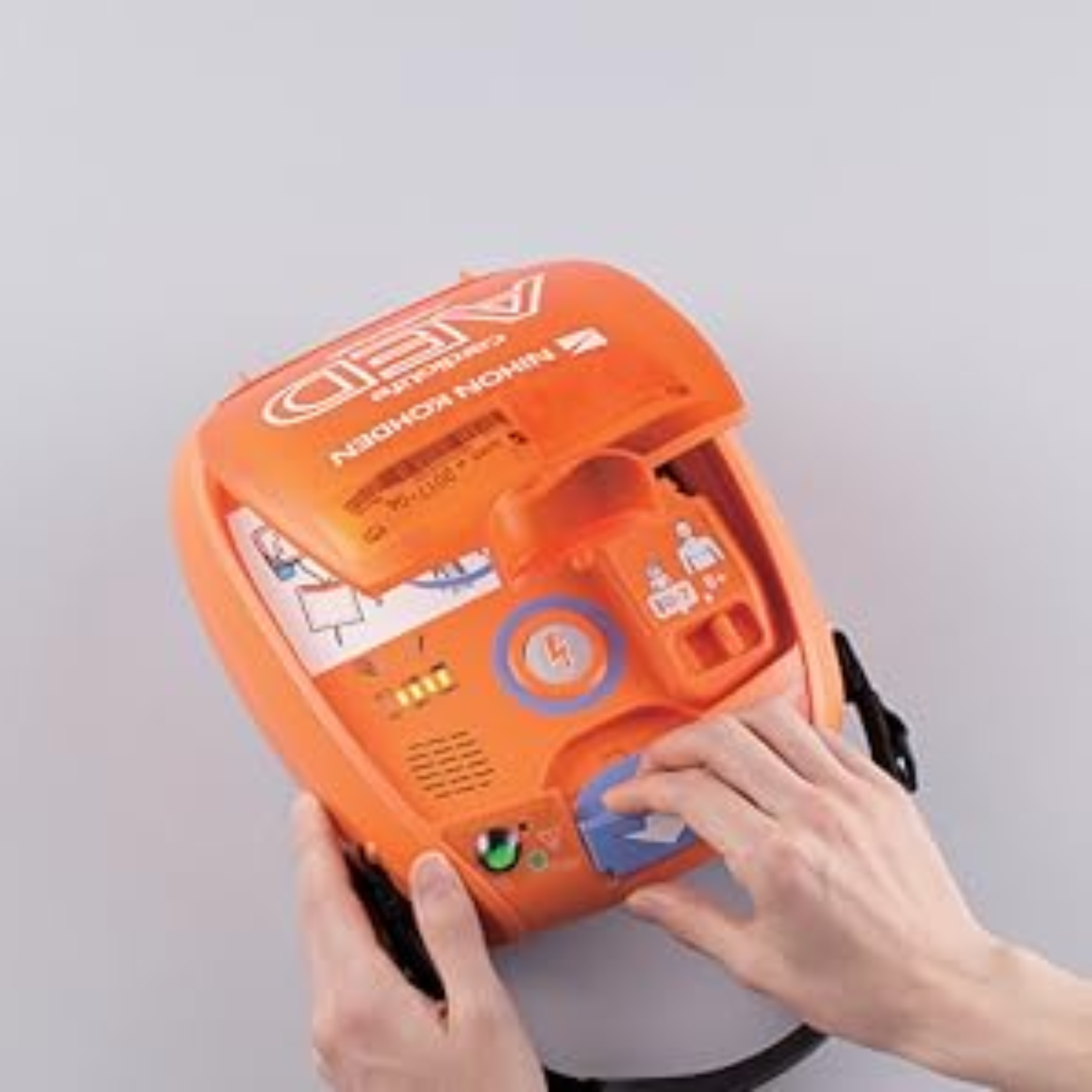 Orange AED device with hands interacting on a gray background